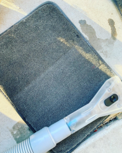 A carpet cleaning tool actively cleaning a dirty car floor mat by Humble Carpet Cleaners in Mesa, AZ