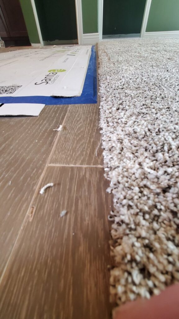 A close-up of a carpet and hardwood floor transition during installation by Carpet Mart of Idaho Falls in Idaho Falls, ID.