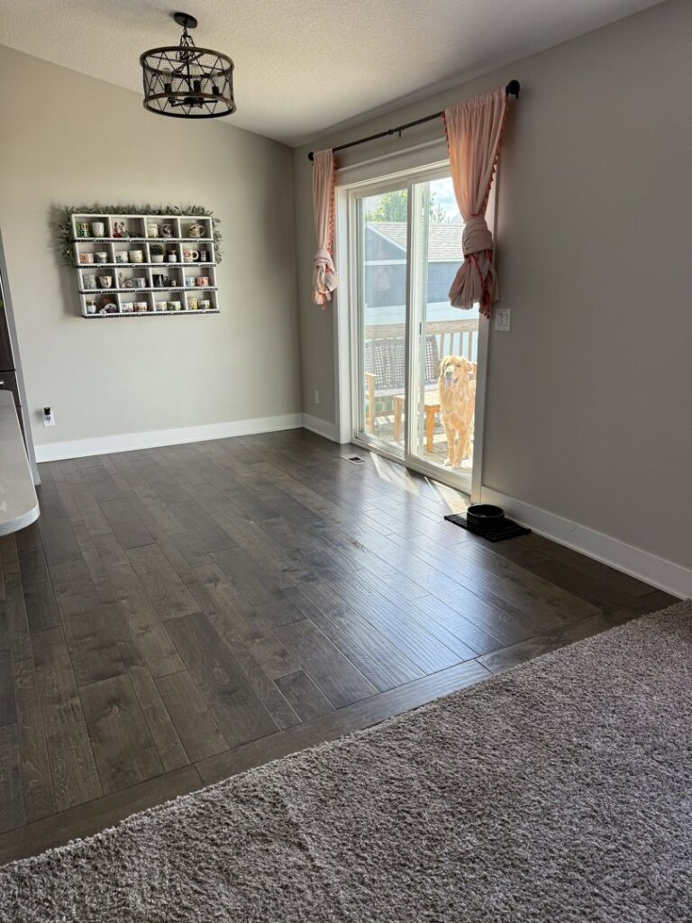A seamless transition between dark hardwood and gray carpet flooring installed by G and L Flooring Plus in Ankeny, IA.