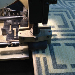 A carpet binding machine finishing the edge of a custom patterned rug at Carpet Ends in West Springfield, MA.