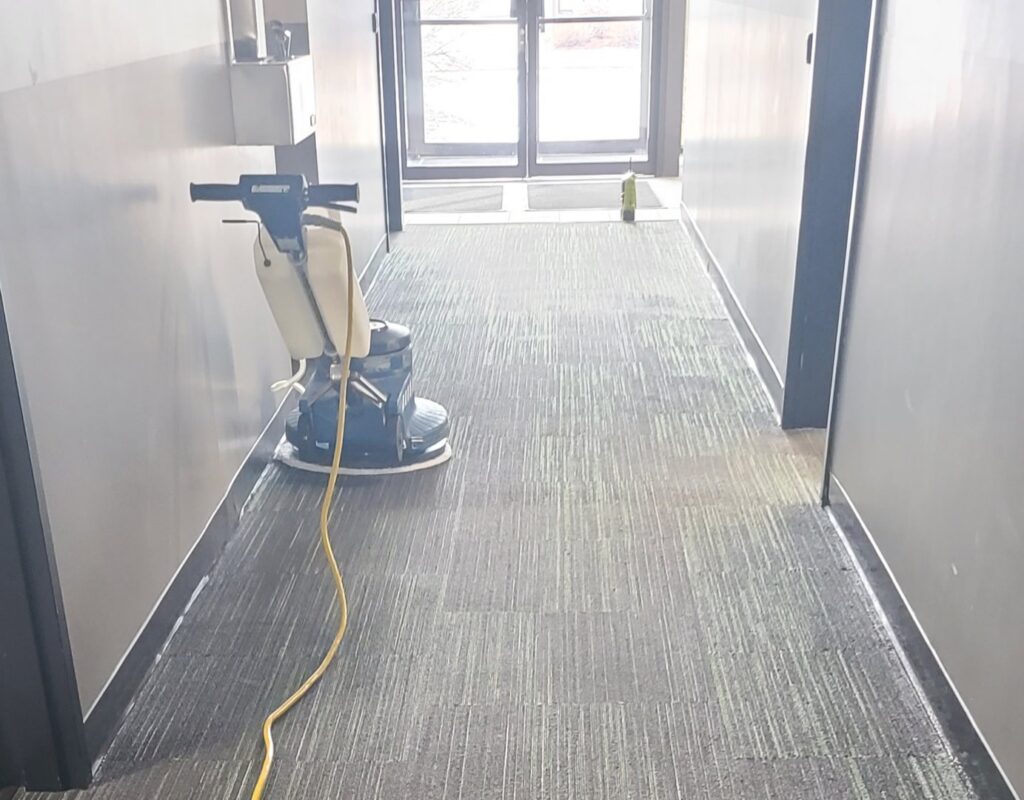 A professional using a floor buffer on a carpeted hallway for deep cleaning by Alaska Dry Carpet in Anchorage, AK.