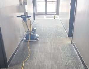 A professional using a floor buffer on a carpeted hallway for deep cleaning by Alaska Dry Carpet in Anchorage, AK.