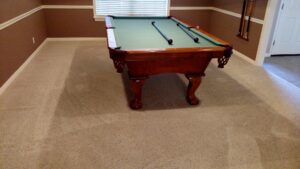 Before and after carpet cleaning around a pool table by Certified Carpet Cleaning & Restoration, showing improved cleanliness in Skiatook, OK.