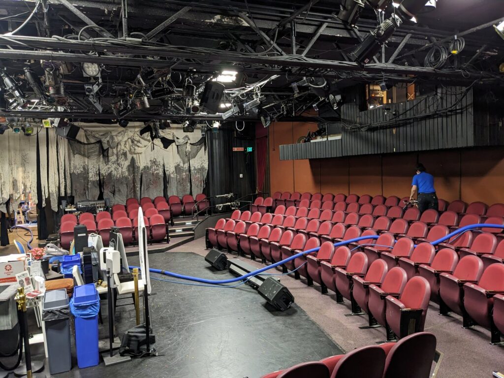 A technician from North Seattle Carpet Cleaning cleaning the carpet in an auditorium in Seattle, WA