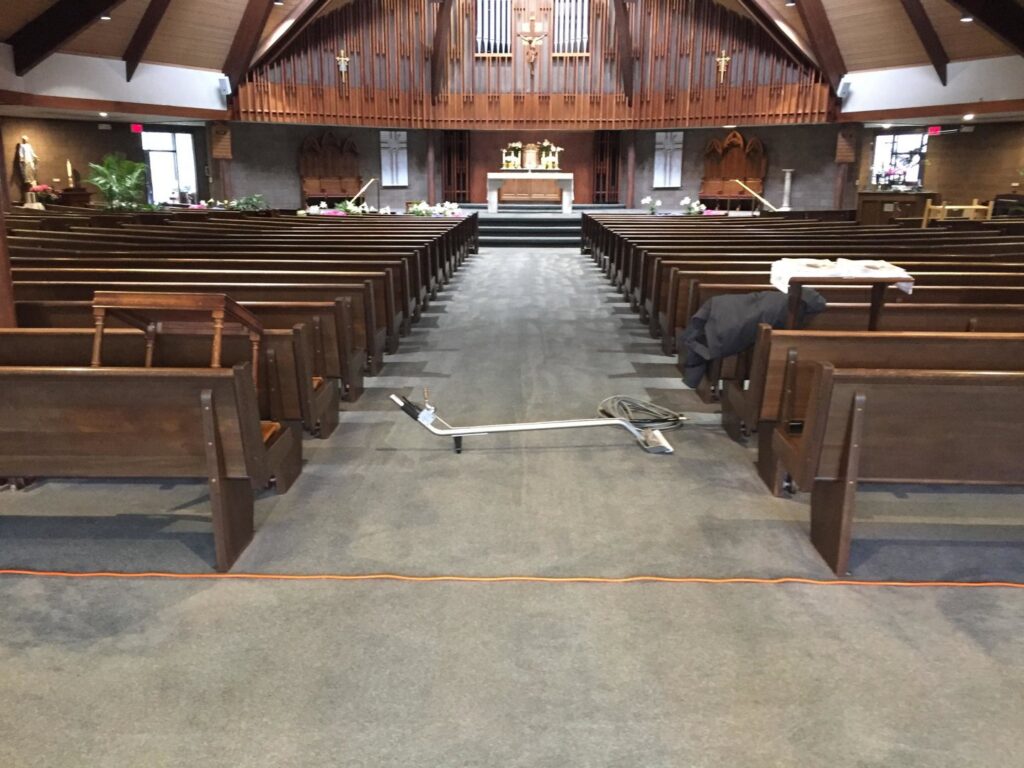 Carpet cleaning equipment and hoses set up in a church aisle, ready for service by Yellow Finch Carpet Cleaning LLC in Dover, NH.