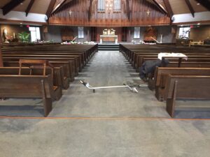 Carpet cleaning equipment and hoses set up in a church aisle, ready for service by Yellow Finch Carpet Cleaning LLC in Dover, NH.