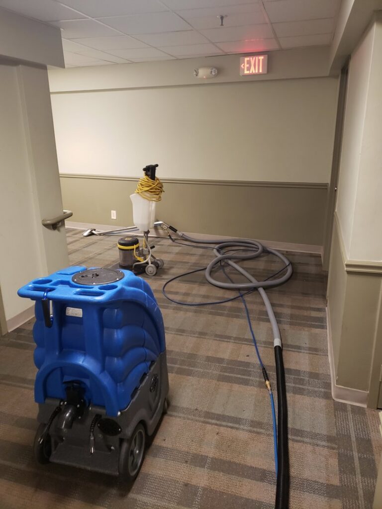 Professional carpet cleaning equipment, including a blue extractor and hoses, set up in a hallway by Fantastic Carpet Cleaning NYC in Ridgewood, NY