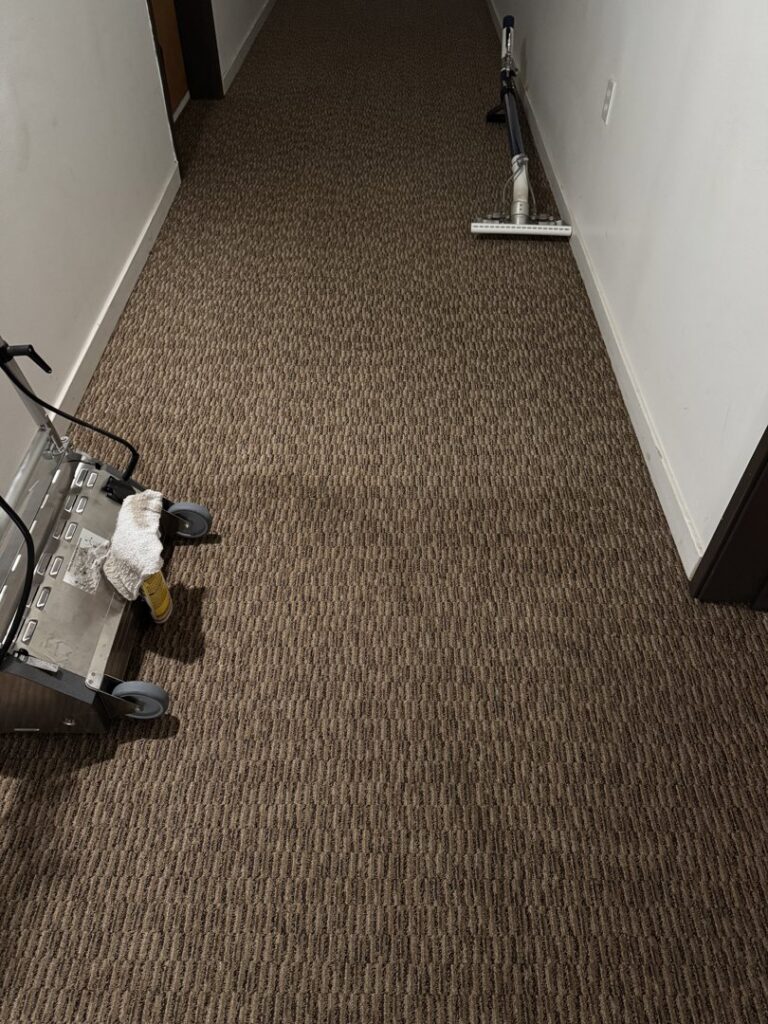 Professional carpet cleaning equipment in a brown patterned carpeted hallway, demonstrating work by Strictly Tile & Carpet Care in Lansing, MI.