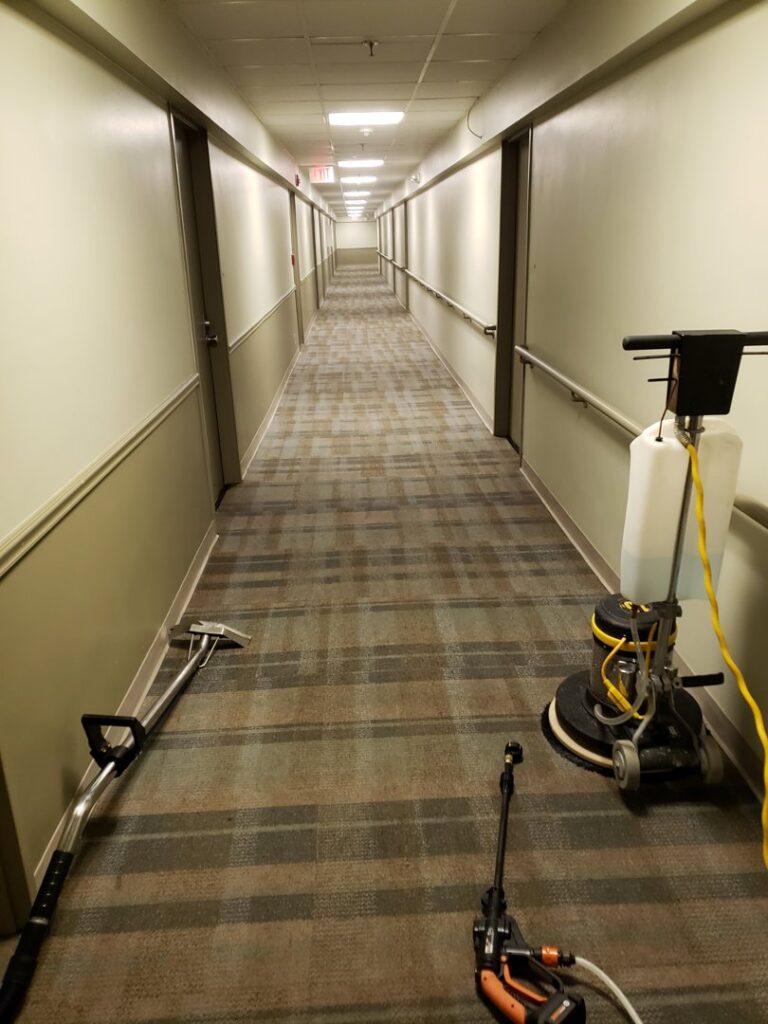 Carpet cleaning equipment, including a wand and floor buffer, set up in a long hallway by Fantastic Carpet Cleaning NYC in Ridgewood, NY