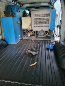 Specialized carpet cleaning equipment and tanks visible inside a service van for Delmac Products Truckmount Service in Bakersfield, CA.