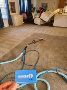 Carpet cleaning equipment and hoses on a freshly cleaned carpet, with a Muscle Cleaning Services business card in Dallas, TX.