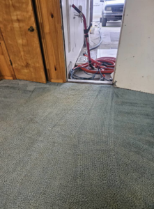 Carpet cleaning hoses and a wand in a doorway, with a service van visible outside for Super Clean Carpet Cleaning in Idaho Falls, ID.