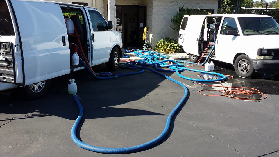 Two Harper's Cleaning Services vans with carpet cleaning equipment set up for a job in Anaheim, CA.