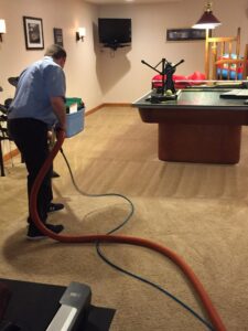 A technician cleaning carpet in a game room with a pool table for Complete Carpet Care in Fort Wayne, IN.