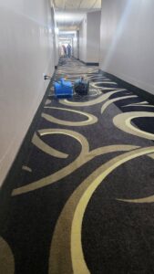 Professional carpet cleaning in a hotel hallway with equipment by InnaCircle in Greensboro, NC.