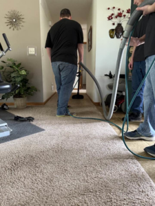 A professional from Sparkling clean using a hose to clean carpet in a residential hallway in Salina, KS.