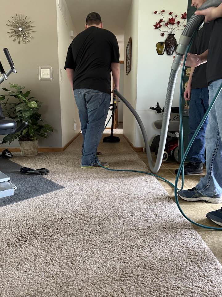 A professional from Sparkling clean using a hose to clean carpet in a residential hallway in Salina, KS.