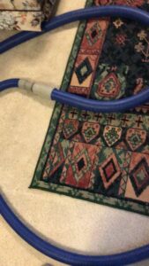A blue carpet cleaning hose laid out on a patterned rug during a service by Kung Fu Carpets and Cleaning Co. in Meridian, ID.