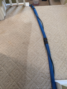 A blue carpet cleaning hose on a carpeted staircase, showing a professional carpet cleaning job by Green Planet Carpet Cleaning in Bloomington, MN.