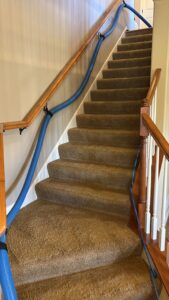 A blue carpet cleaning hose running up carpeted stairs during a job by Ohana Clean llc in Saint Paul, MN
