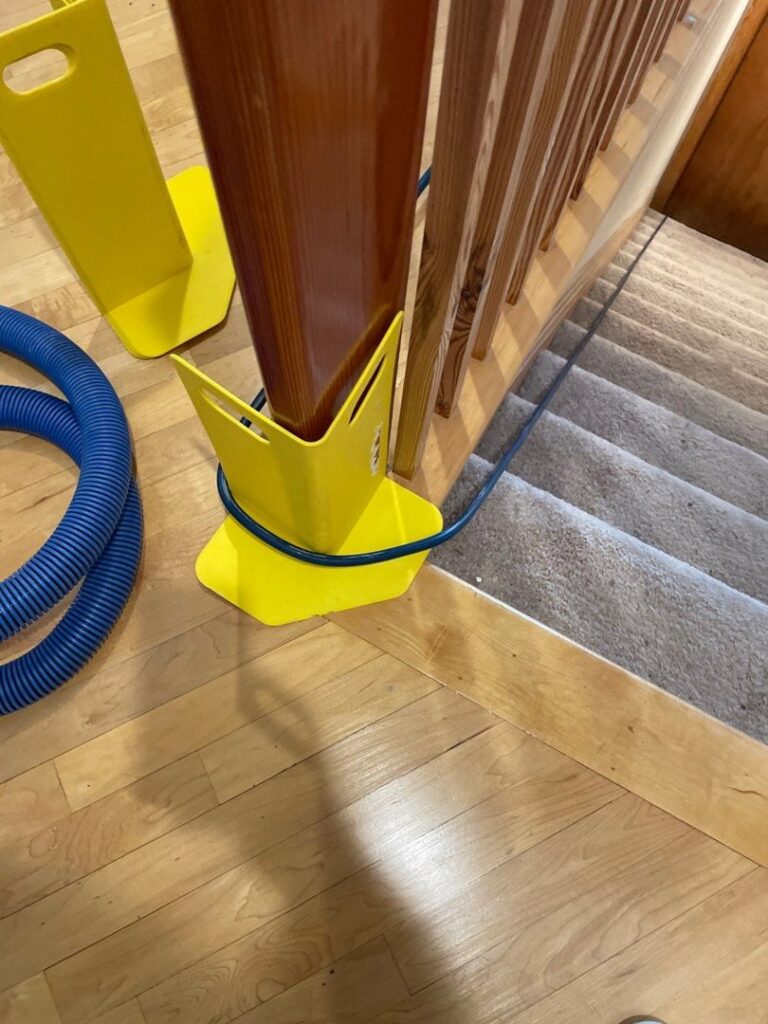 Carpet cleaning hose with corner protectors on a carpeted staircase by Inlet Carpet Care in Virginia Beach, VA