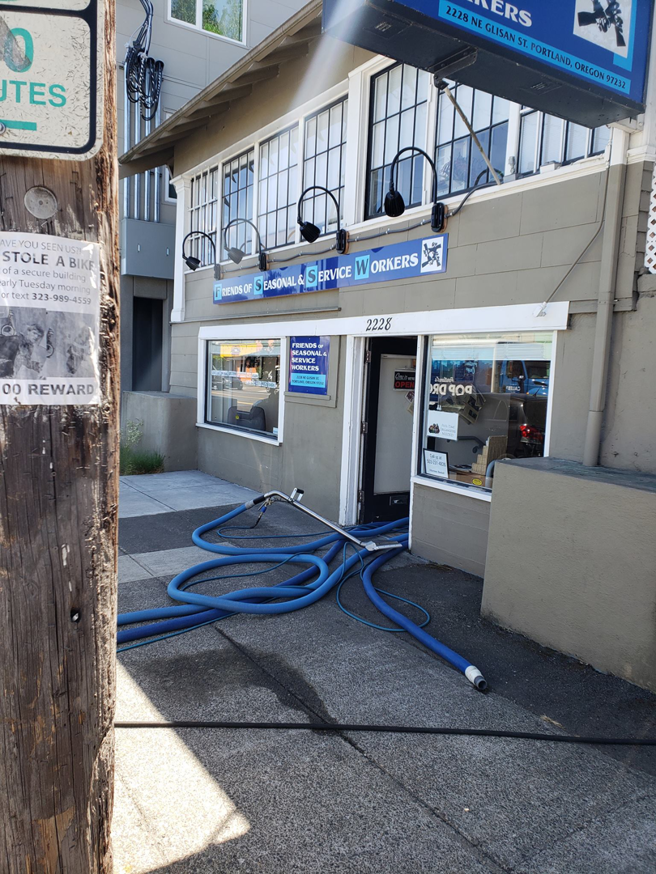Carpet cleaning hoses extending from a Green Steam Carpet Clean van into a commercial building in Portland, OR.