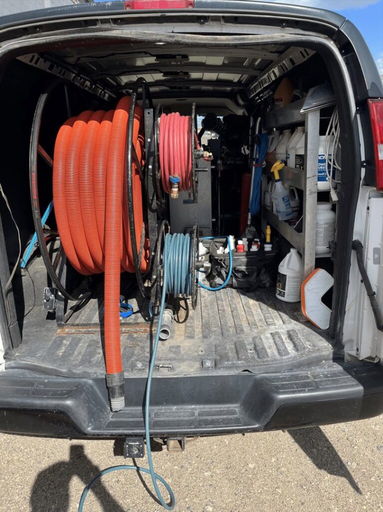 Coiled hoses and cleaning supplies neatly stored in the back of a Carpet Master service van in Aberdeen, SD.