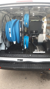 Carpet cleaning hoses on reels and a cleaning wand in the back of a service van for Delmac Products Truckmount Service in Bakersfield, CA.