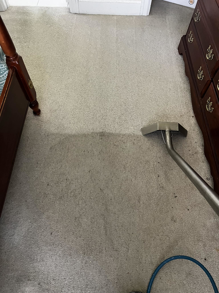 Carpet cleaning in progress in a bedroom, showing a clean strip next to a dirty area by Xtreme Klene Carpet & Upholstery Cleaning in Montgomery, AL.