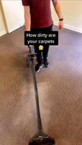 A professional cleaning a dirty brown carpet with a cleaning wand for Lincoln Carpet Cleaning Pros in Lincoln, NE.