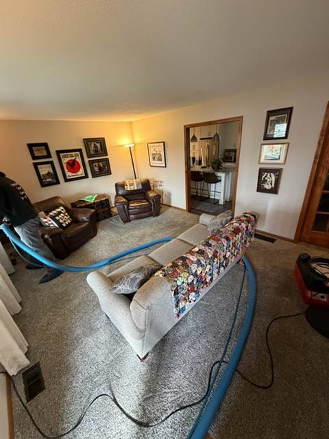 A professional performing carpet cleaning in a living room with equipment for Hartford's Carpet Cleaning in Toledo, OH