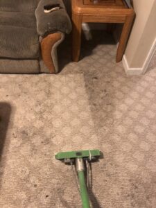 A carpet cleaning wand in action on a dirty living room carpet, performed by ISteam Carpet Care in Chattanooga, TN.
