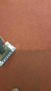 A carpet cleaning wand in action, showing a clean path on a red carpet by Lund's Carpet Cleaning in Spokane, WA.