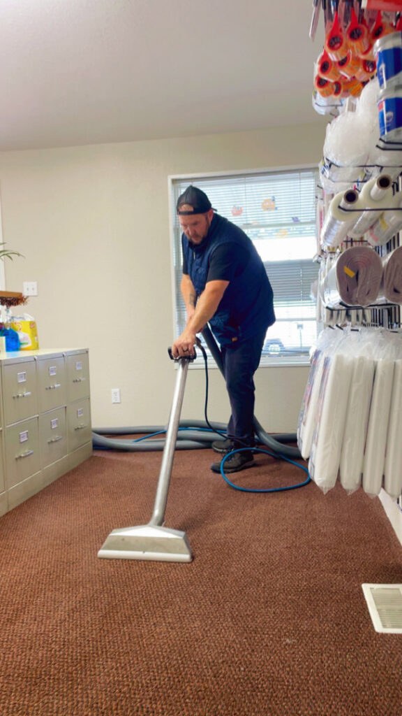A technician performing professional carpet cleaning with a wand on a brown carpet for Mountain View Carpet Care LLC in Vancouver, WA.