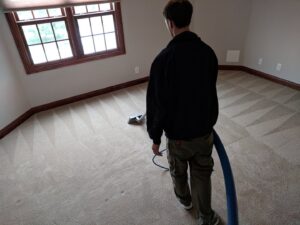 A technician performing carpet cleaning, showing the distinct clean lines on the carpet, by Premium Carpet Care in Lincoln, NE.