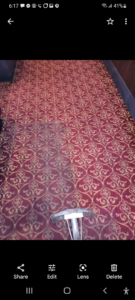 A carpet cleaning wand on a red patterned carpet, showing a clean path by Sunshine Carpet Cleaning in Waterbury, CT.