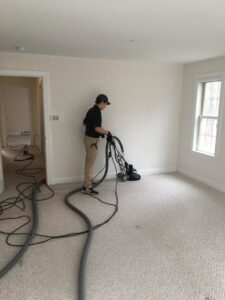 A professional from Yellow Finch Carpet Cleaning LLC performing carpet cleaning with specialized equipment in a room in Dover, NH.