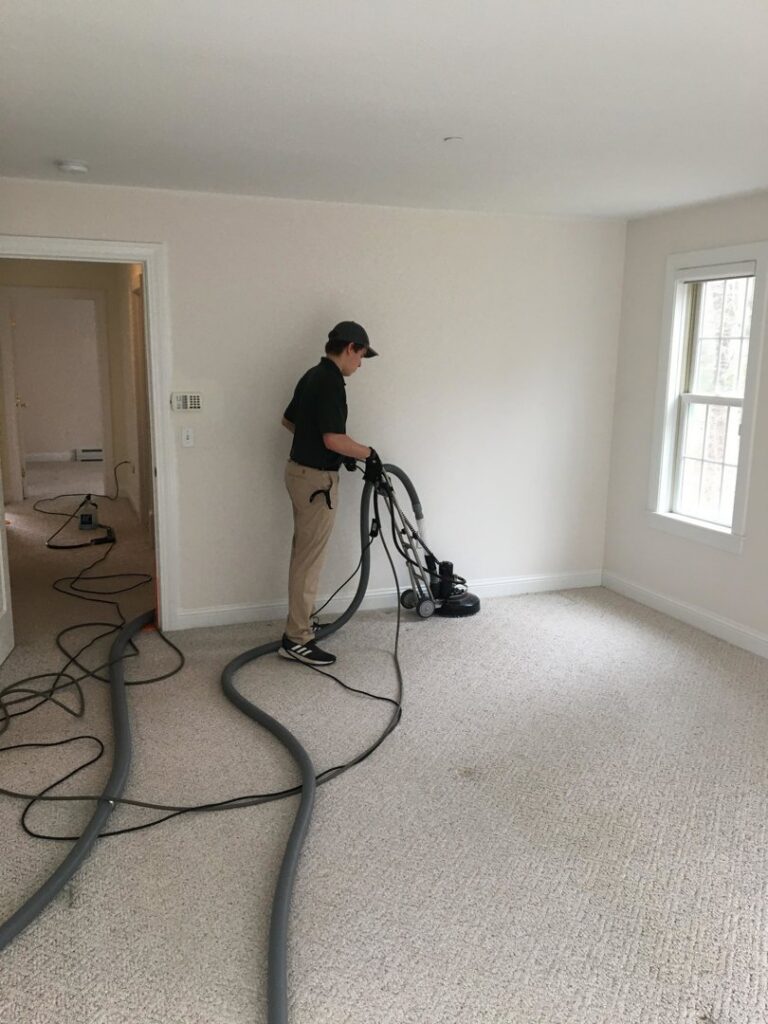 A professional from Yellow Finch Carpet Cleaning LLC performing carpet cleaning with specialized equipment in a room in Dover, NH.