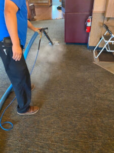 A professional performing a carpet cleaning job with a steam wand at First Choice Janitorial Services in Vancouver, WA.