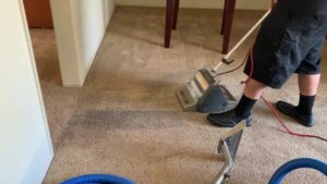 A professional performing a carpet cleaning job with a machine, showing a clean path, by Mark it Clean Carpet & Upholstery Cleaning Long Beach, CA.
