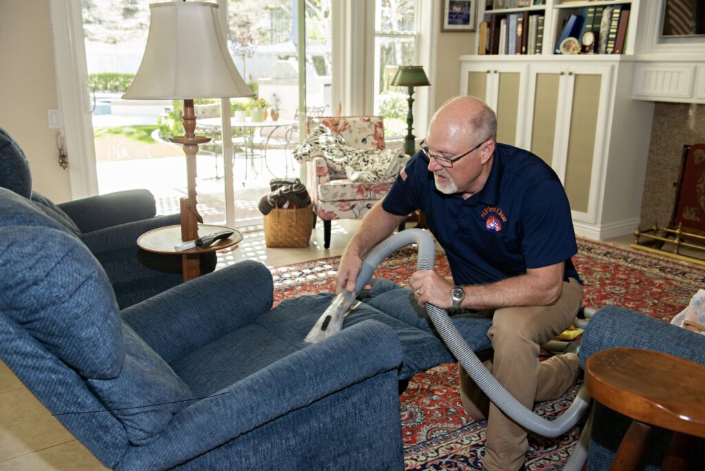 A technician from First Clean SC cleaning a large carpet in a living room with a marina view in North Charleston, SC.