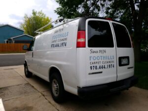 A close-up view of a carpet cleaning machine in operation, showing a clean path on a light-colored carpet by Foothills Steam Carpet Cleaners in Fort Collins, CO.