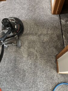 A carpet cleaning machine working on a grey carpet, showing the cleaned area by Carpet Master in Aberdeen, SD.