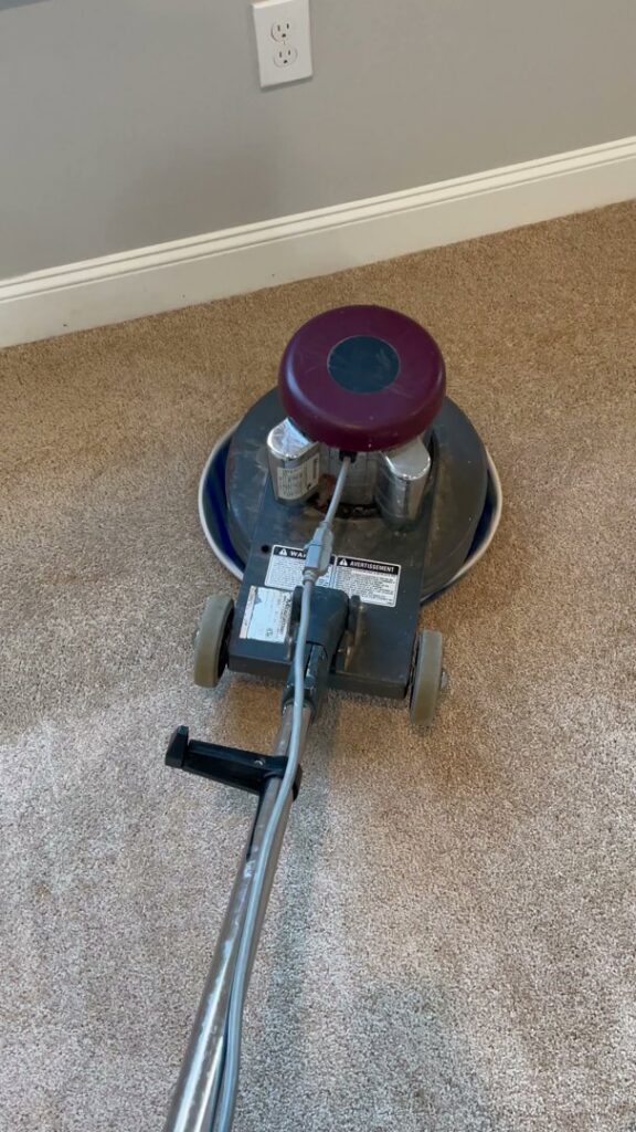 A professional carpet cleaning machine in operation on a light brown carpet by Floor Medics in Huntsville, AL
