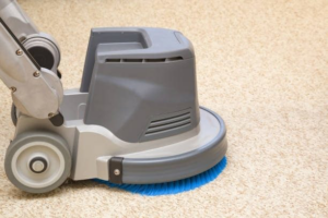 A professional carpet cleaning machine with a blue brush head cleaning a light-colored carpet in Colorado Springs, CO by Rocky Mountain Dry Carpet Cleaning.