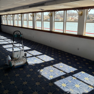 A professional carpet cleaning machine on a patterned blue carpet in a large room, demonstrating services by Pro Clean Group in Knoxville, TN.