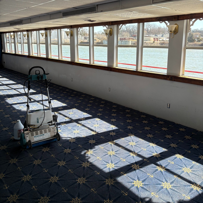 A professional carpet cleaning machine on a patterned blue carpet in a large room, demonstrating services by Pro Clean Group in Knoxville, TN.