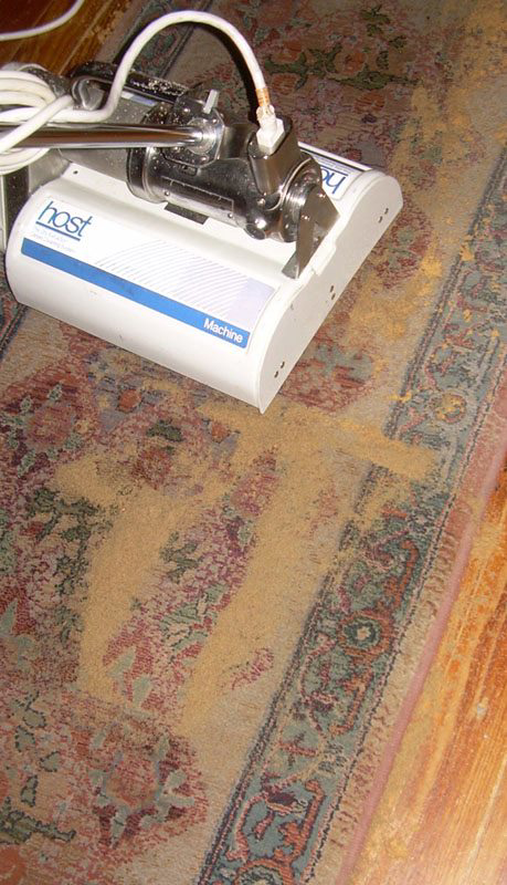 A close-up of a professional carpet cleaning machine working on a dirty patterned rug by A Better Carpet Cleaning in Reno, NV.