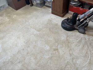 A carpet cleaning machine actively working on a dirty carpet, showing the cleaned area by Carpet Master in Aberdeen, SD.