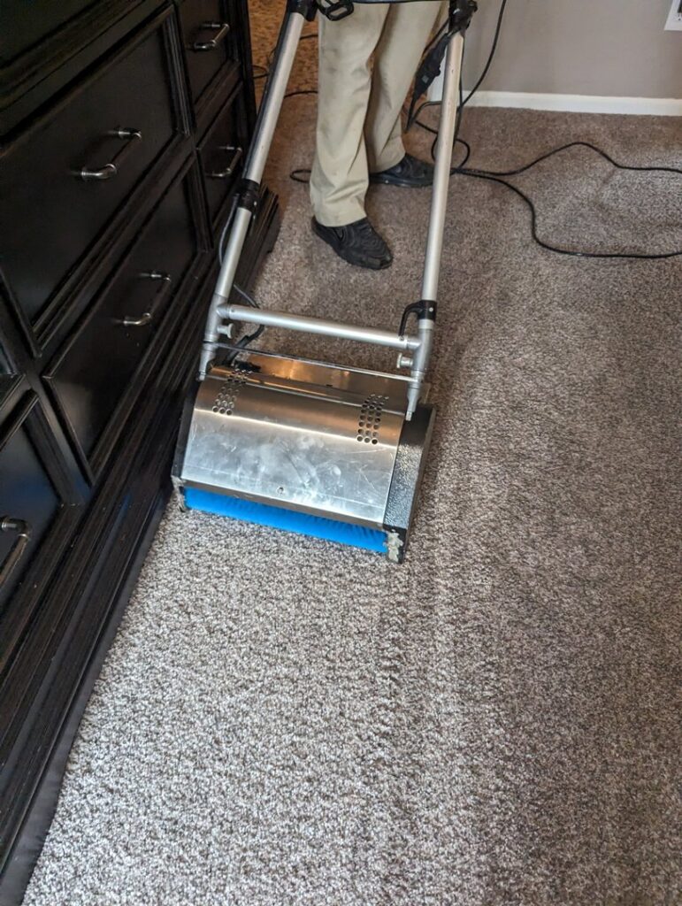A professional carpet cleaning machine in use, cleaning carpet next to furniture by R&W Carpet Cleaning & Water Extraction in Independence, MO.